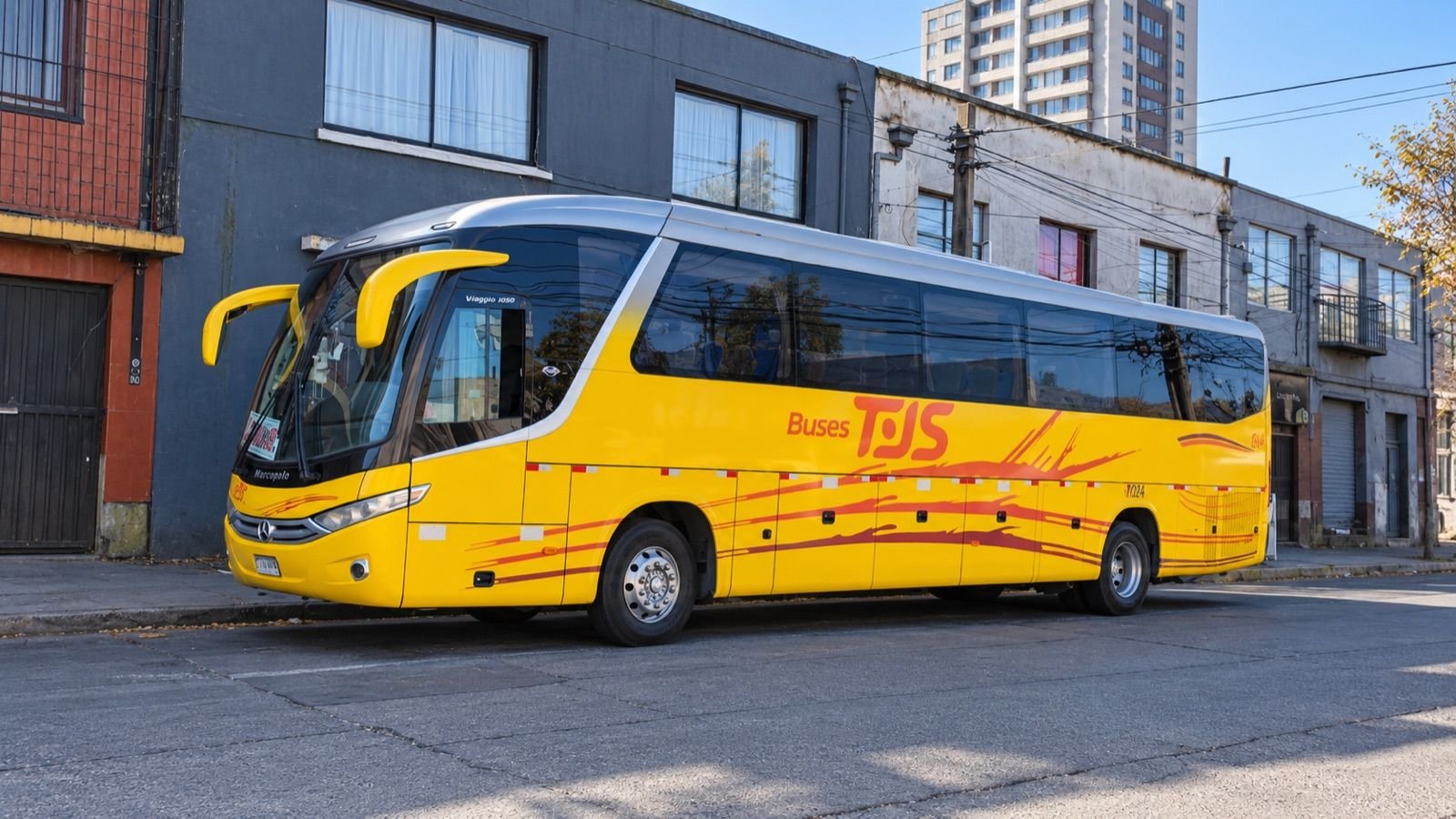Bus amarillo de Buses TJS estacionado en una calle urbana